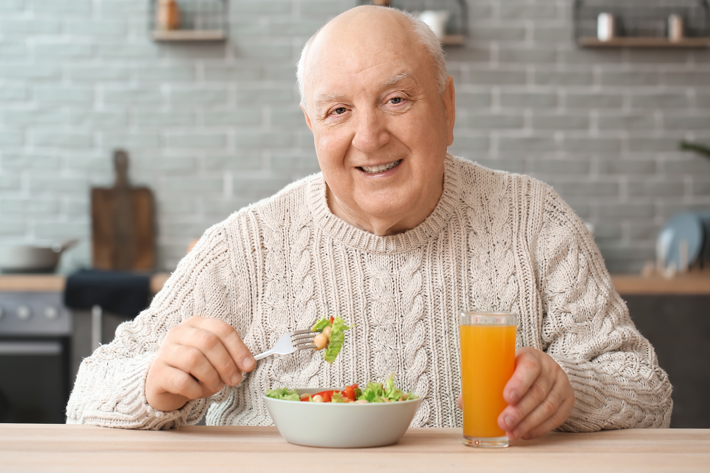 Uśmiechnięty senior z apetytem je pięknie podany posiłek